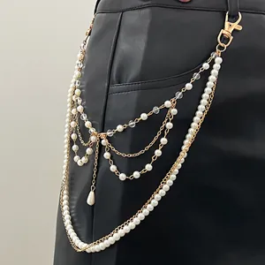 Dettaglio della catena in vita multistrato con finte perle e oro su pantaloni di pelle