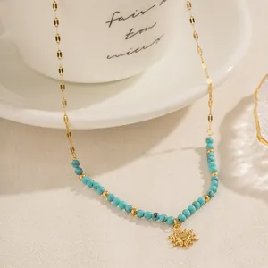 Gros plan collier perles turquoise avec pendentif soleil doré sur chaîne en titane