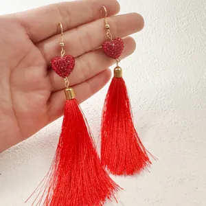 Gros plan détaillé montrant des boucles d'oreilles cœur rouge vif avec de longs pompons