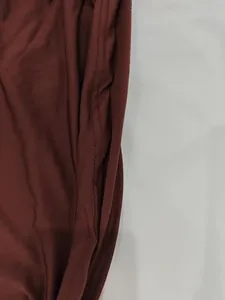 Detailed macro shot of the durable double-stitched seam on burgundy dress fabric