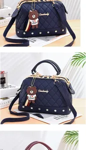 Detailed view of navy blue quilted pillow handbag with a cute cartoon bear charm ornament