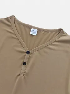 Détail rapproché de l'encolure en V d'un t-shirt kaki pour hommes avec des boutons.