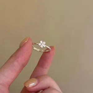 Dainty silver flower ring with sparkling zircon stones worn on finger