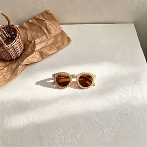 Detailed view of children's retro sunglasses with brown lenses and checkerboard pattern