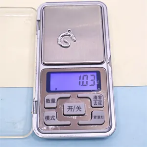 Detalle macro de un dije de letra G de aleación de plata que pesa 1,03g en escala