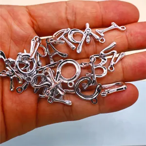 Vista de cerca de veintiséis colgantes de aleación de plata con letras para joyería DIY