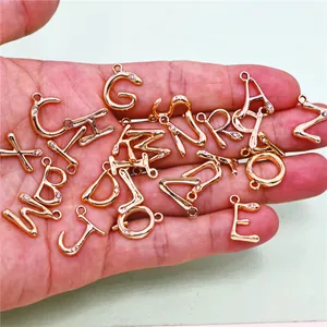 Vista detallada de dijes de alfabeto dorados con pedrería para la creación de joyas DIY.
