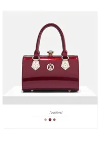 Front view of an elegant wine red patent leather handbag featuring gold hardware accents