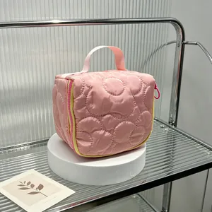 Close-up detail of pink quilted cosmetic bag with floral stitching on a display stand