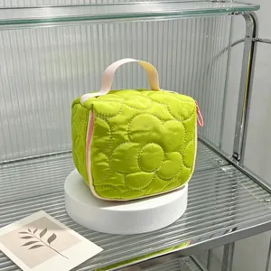 Detailed macro view of a green quilted flower cosmetic bag with a stylish pink handle