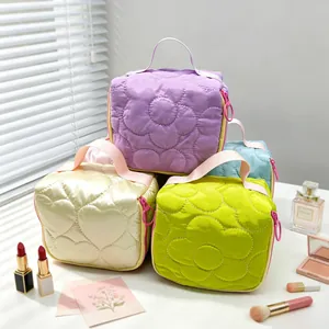 Stacked quilted cosmetic bags with floral patterns shown with makeup accessories