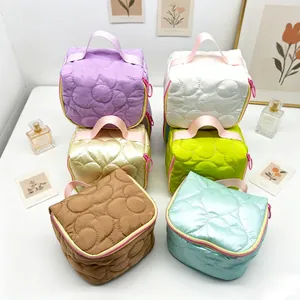 A diverse group of quilted flower makeup bags in various pastel colors on a white surface