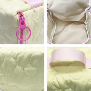 Close-up details of quilted makeup bag showing pink zipper and interior lining