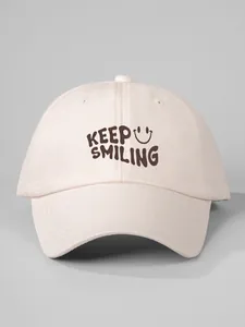 Close-up of a beige baseball cap featuring a 'Keep Smiling' print and smiley face