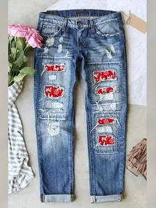 Detailed view of distressed denim jeans with festive red Christmas Ho Ho Ho patches.