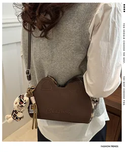 Détail du sac bandoulière en peluche oreilles de chat marron avec breloque nœud léopard