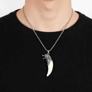 Close-up of vintage wolf tooth pendant on stainless steel chain over black sweater