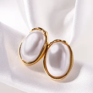 Macro view of French vintage gold oval stud earrings featuring large white faux pearls and texture