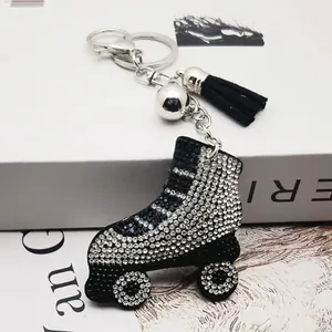 Detalle de un llavero de patín de ruedas con diamantes de imitación, borla negra y cascabel plata