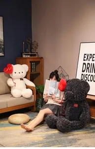 Detail view of two large plush teddy bears holding red heart balloons in a home setting