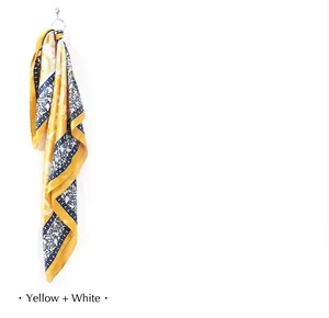 Detail view of a retro paisley print silk square scarf in yellow and white drape