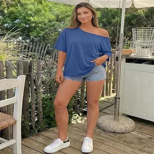 Model wearing a stylish blue off-shoulder loose fit T-shirt in an outdoor patio setting.