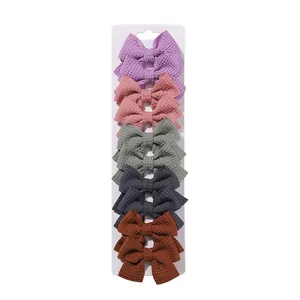 Set of 10 waffle texture fabric bow hair clips for girls in various muted colors.