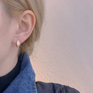 Elegant small gold hoop earrings with white drip oil inlay on female ear