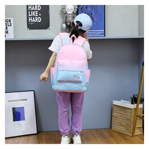 Detail shot of a pink and blue gradient backpack with unicorn prints worn by a child.