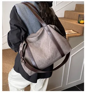 Vista dettagliata di una grande borsa hobo da pendolare in tela marrone con manici in pelle