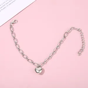 Close-up view of a minimalist silver heart pendant bracelet on a stylish pink backdrop.