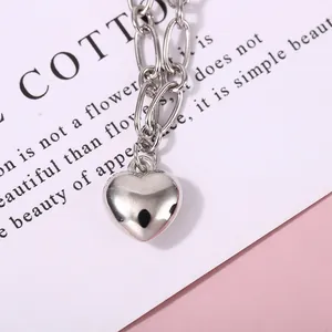 Macro detail of polished silver heart pendant on a minimalist chain link bracelet
