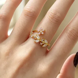 Gros plan d'une bague ouverte dorée avec motifs de feuilles et fleurs en zircone