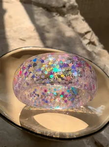 Detailed macro shot of a transparent resin bangle with colorful iridescent heart sequins