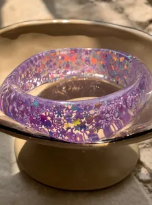 Close-up of purple resin bangle with colorful holographic glitter heart and star sequins.
