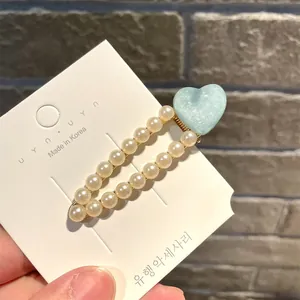 Nahaufnahme einer eleganten Perlen-Haarspange mit hellblauem Glitzerherz auf Karte