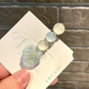 Nahaufnahme einer Haarspange im Ozean-Stil mit Muschel und schillernden Perlen