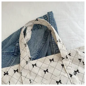 Detail of quilted corduroy tote bag with black bow pattern and diamond grid