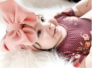 Close-up detail of a large pink bubble flower fabric bow headband on a newborn baby
