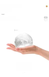 Detail einer großen, klaren Eiskugel mit 6 cm Durchmesser für Whiskey in der Hand