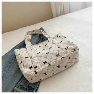 Close-up of a quilted tote bag featuring black bow embroidery on white lifestyle setting