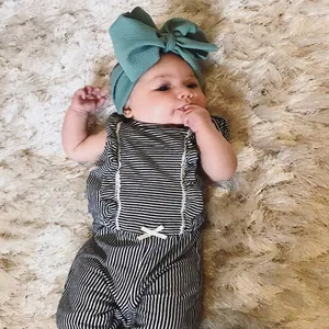 Detailed view of baby girl wearing oversized green textured bow headband for photography.