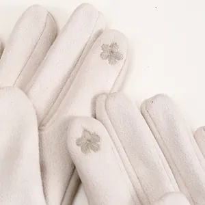 Detailed view of elegant flower embroidery on beige suede winter gloves for ladies