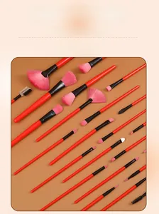 Detailed view of a professional 24-piece makeup brush set with red handles and pink bristles.