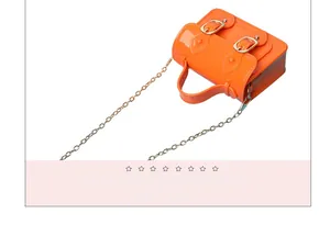 Detail showing the glossy texture of a mini orange jelly satchel bag with chain