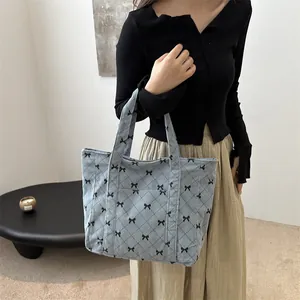 Blue corduroy tote bag with diamond quilting and black bow patterns for women.