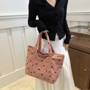 Stylish pink corduroy tote bag with black bow pattern and elegant quilted diamond stitching