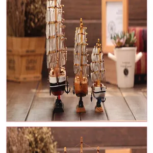 Detail view of three sizes of Mediterranean style wooden sailing boat models on a desk