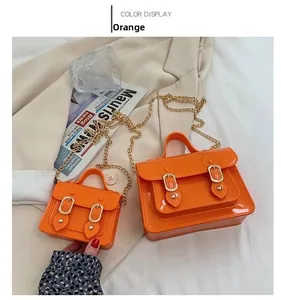 Detail of orange jelly Cambridge satchel bags with gold chain straps in two sizes