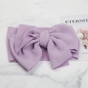 Close-up detail of a soft lavender textured bubble fabric bow headband for infants